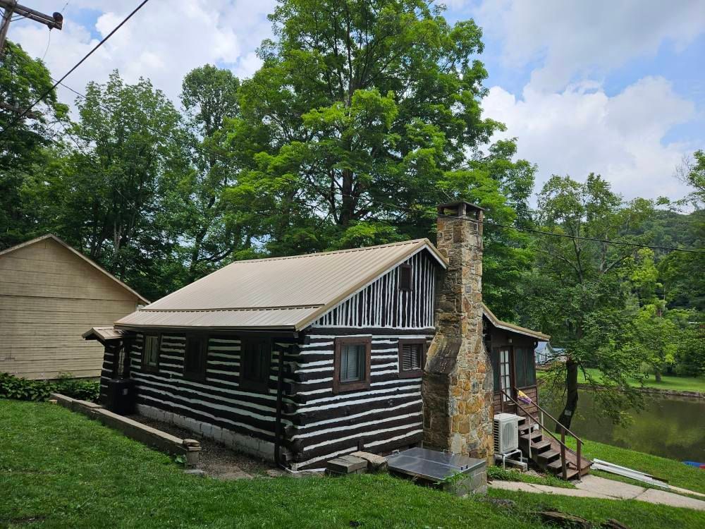 A small log cabin is sitting on top of a lush green hill.