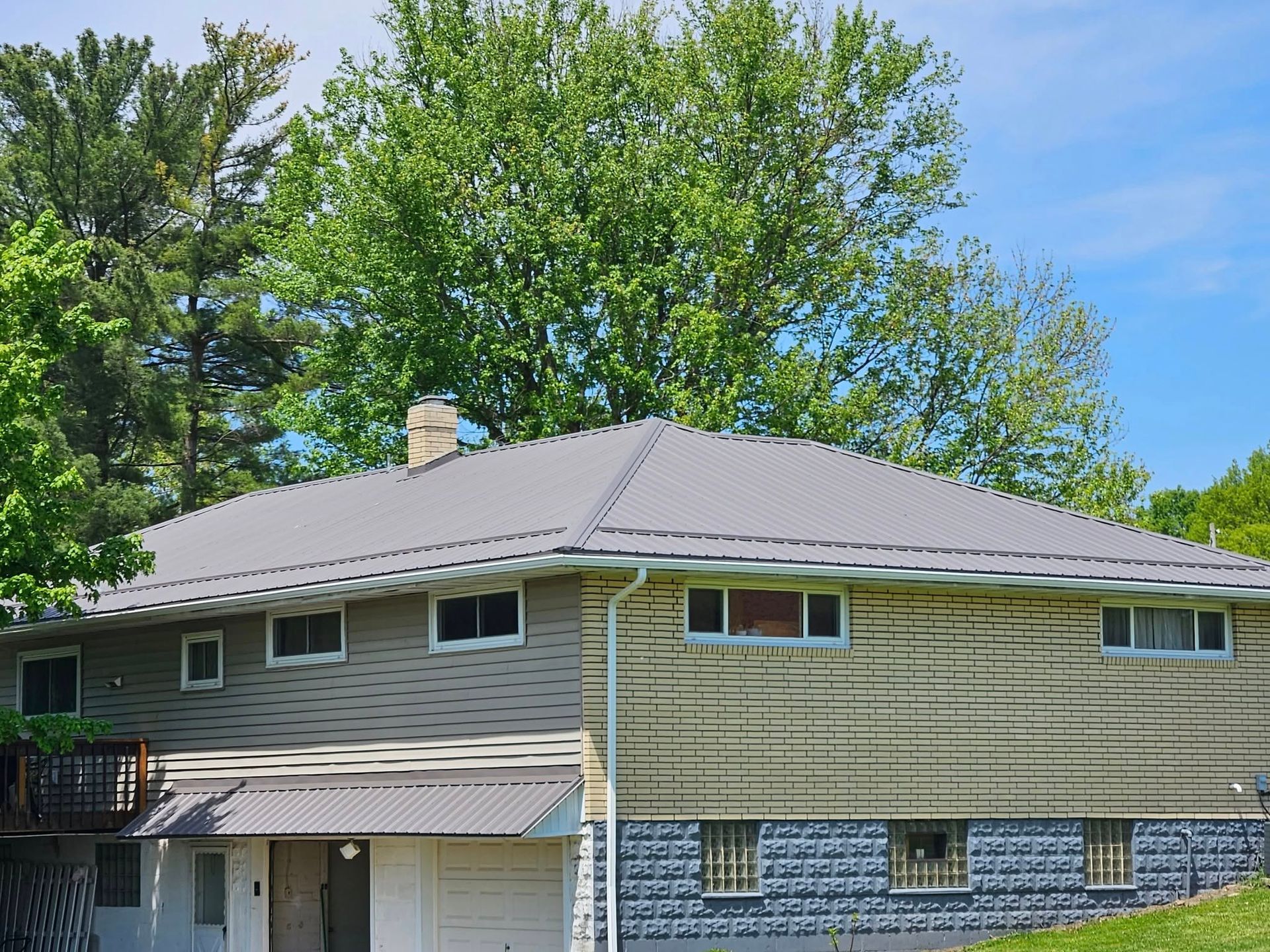 A house with a gray roof and trees in the background