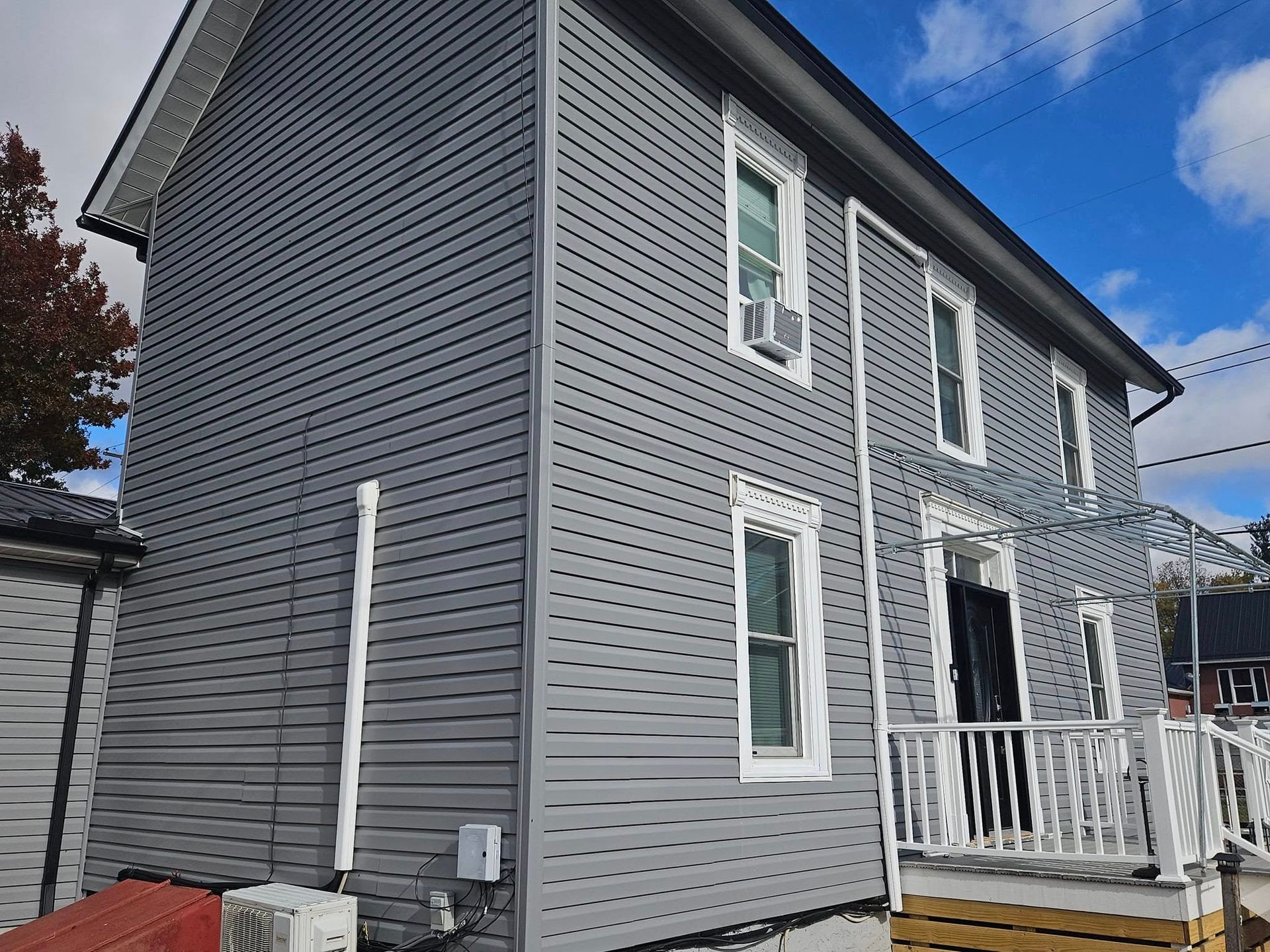 A large gray house with a balcony and a blue sky in the background
