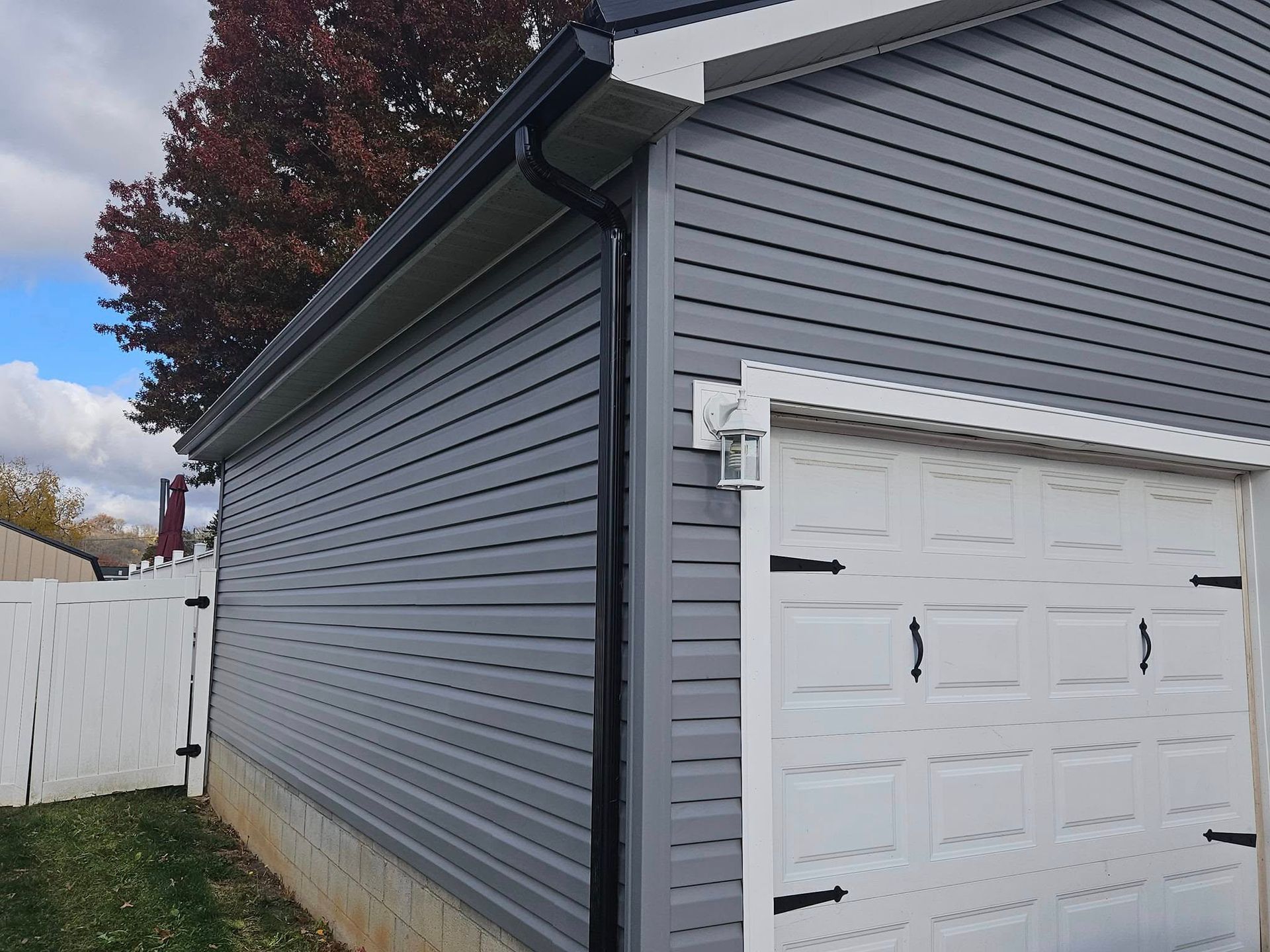 A garage with a gray siding and a white garage door