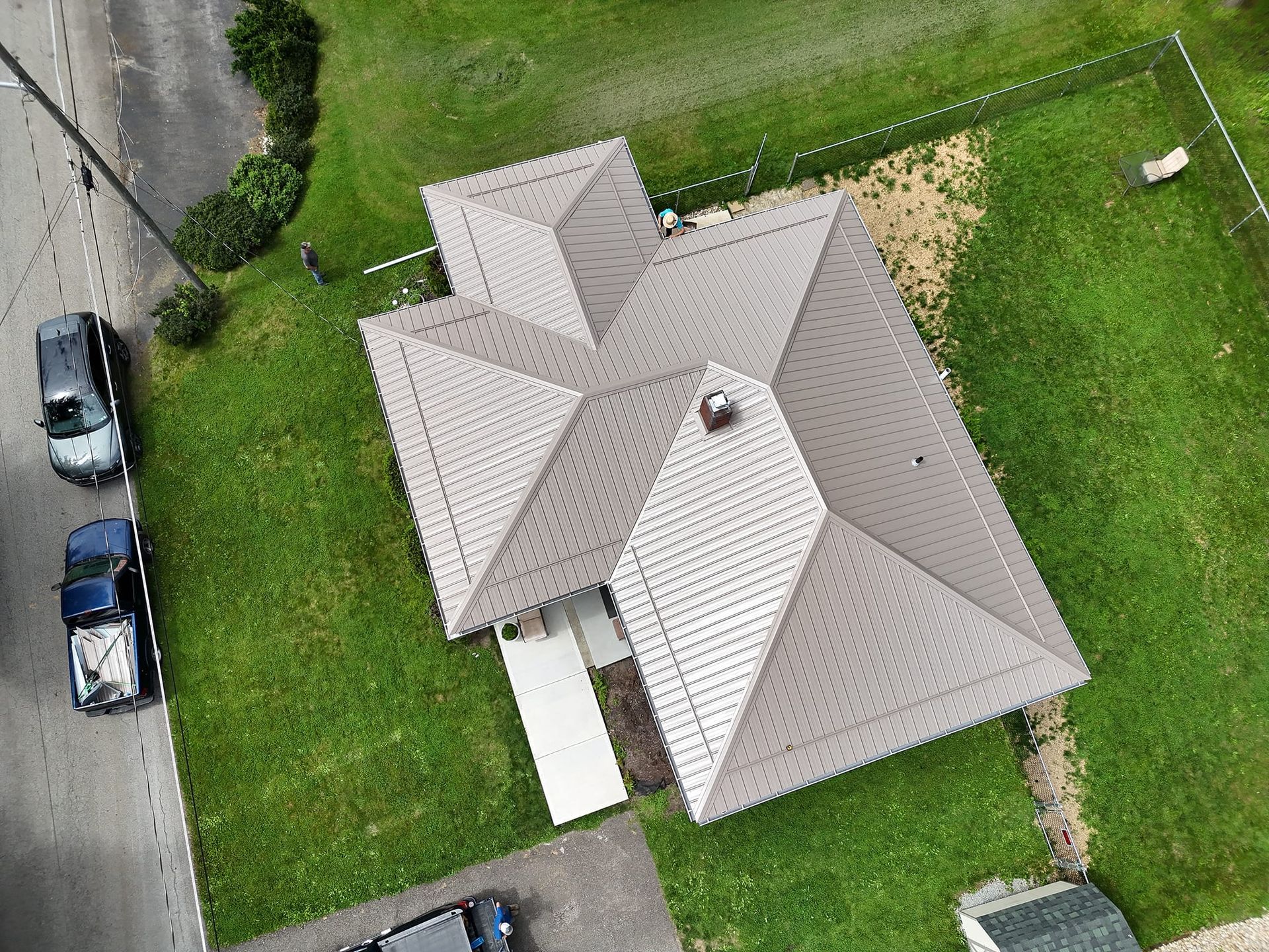 An aerial view of a house with a roof and a lot of grass.