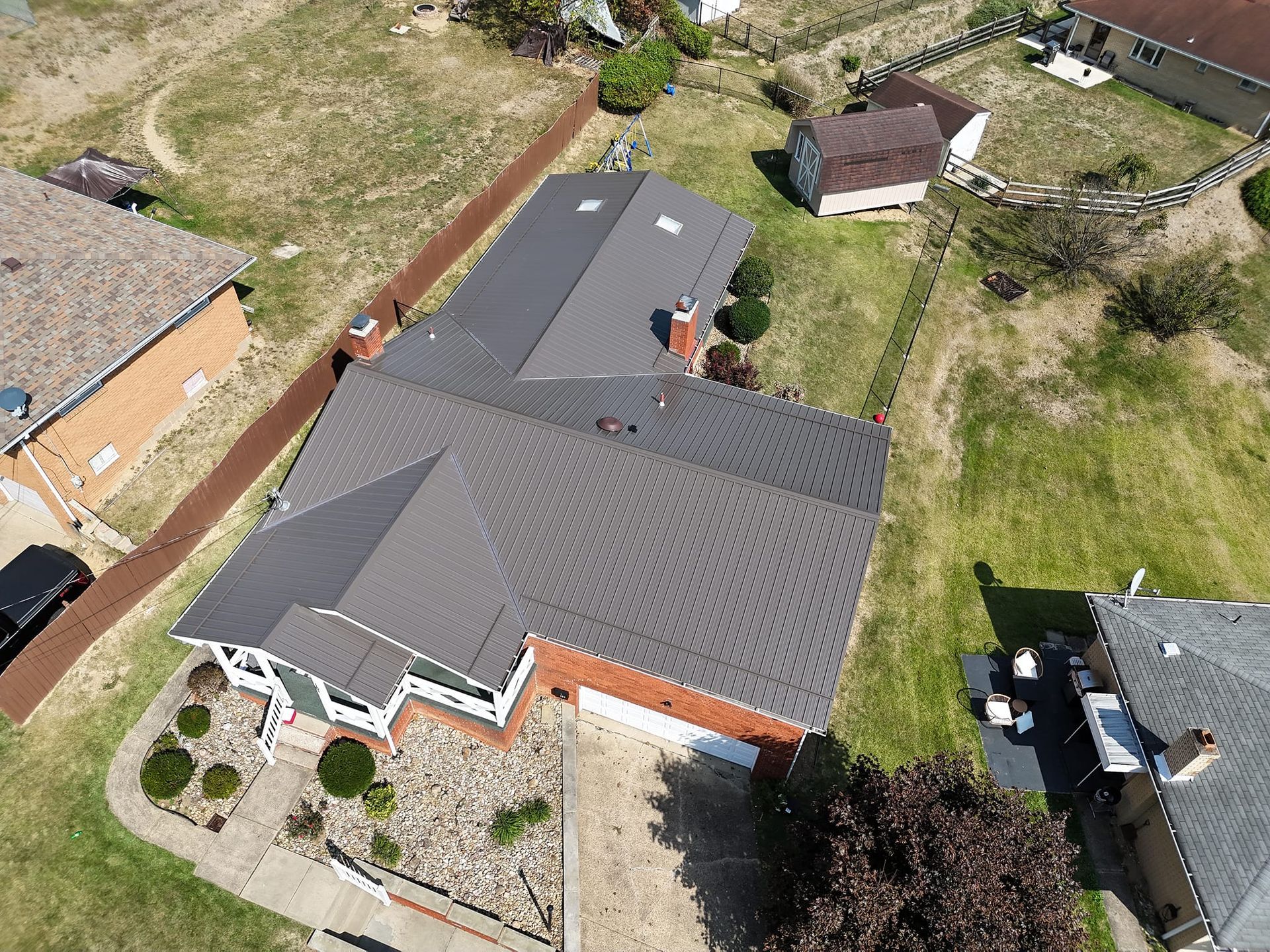 An aerial view of a house with a gray roof in a residential area.