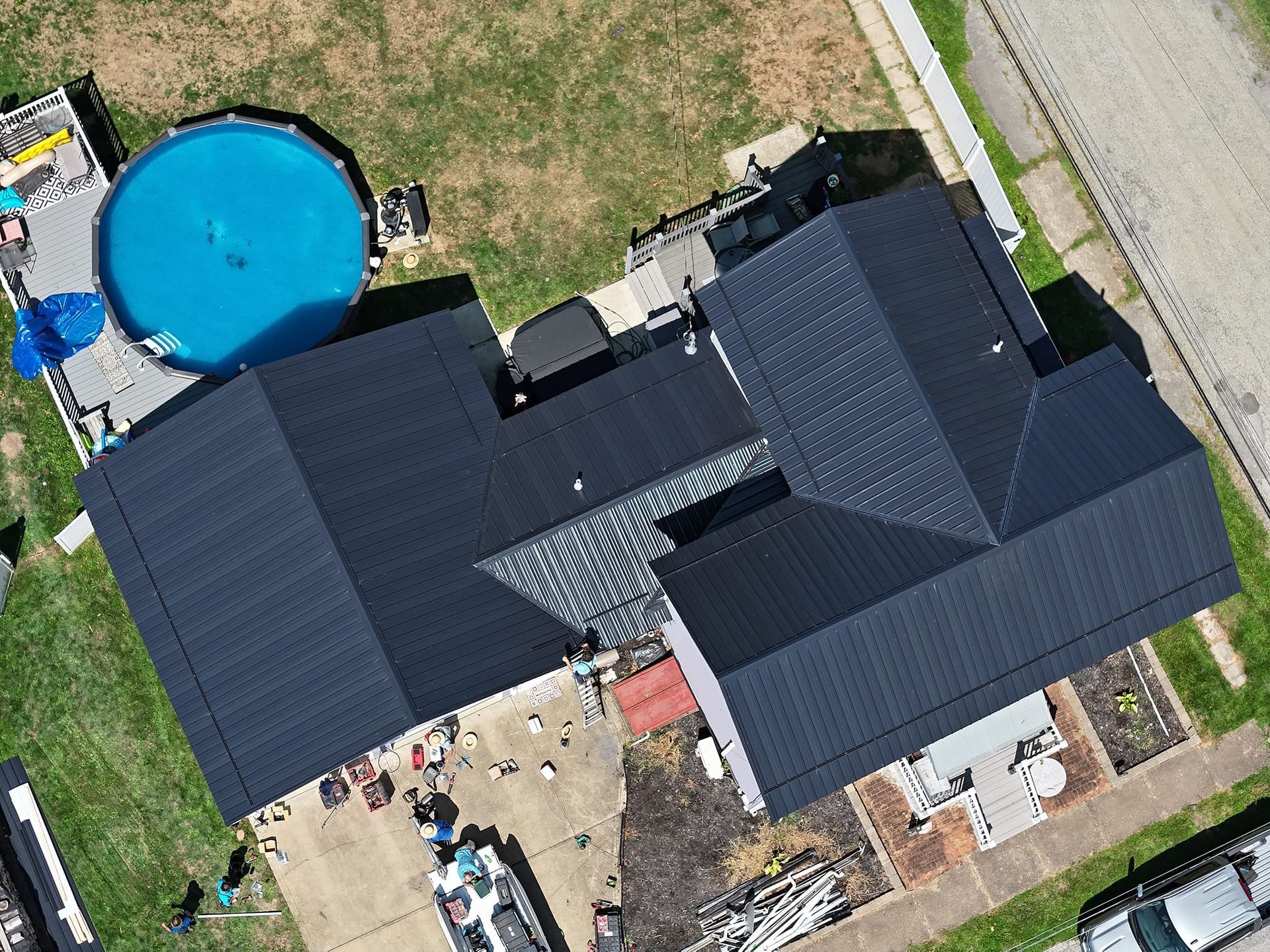 An aerial view of a house with a black roof and a pool.