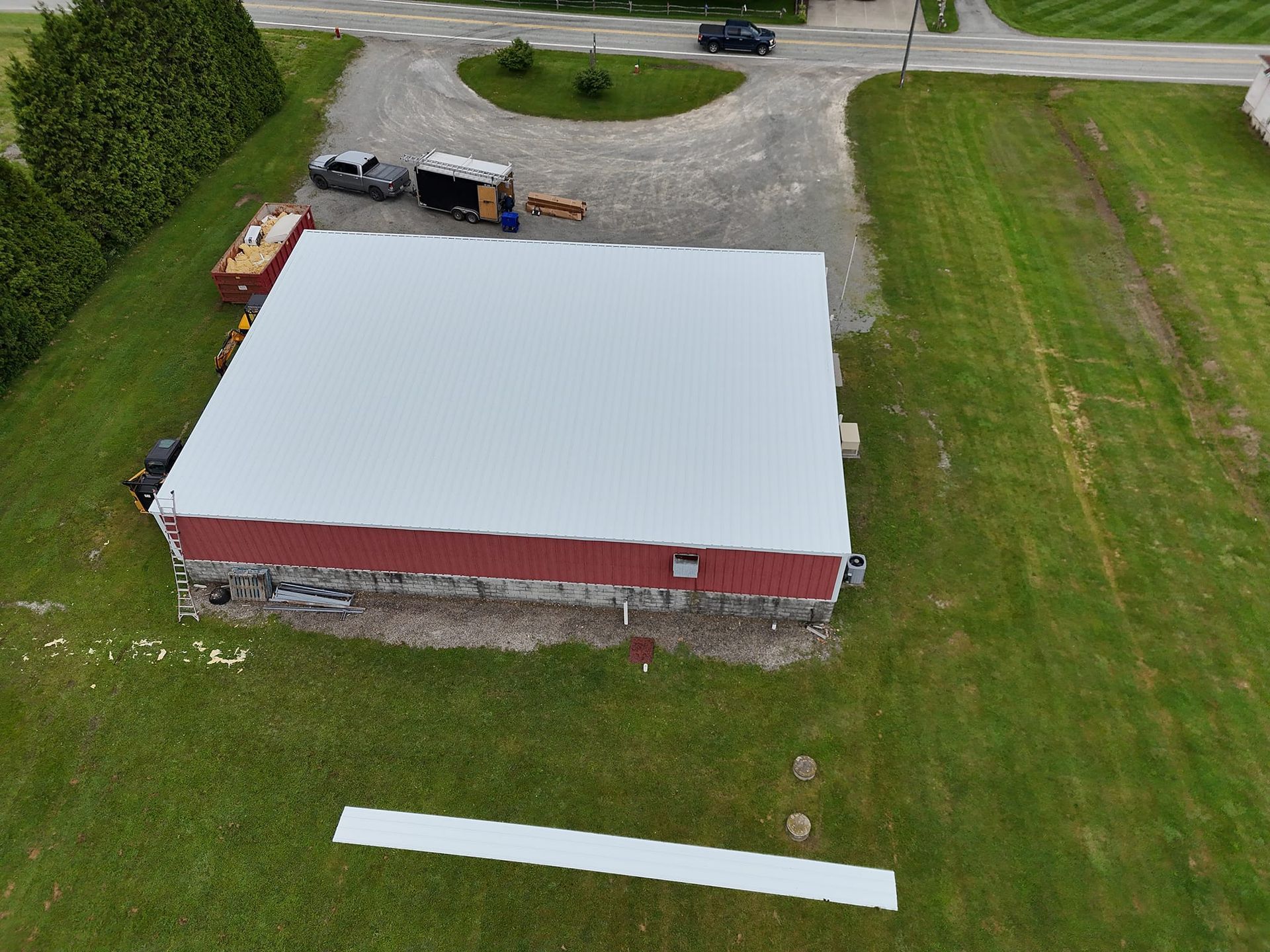 An aerial view of a building with a white roof in a grassy field.
