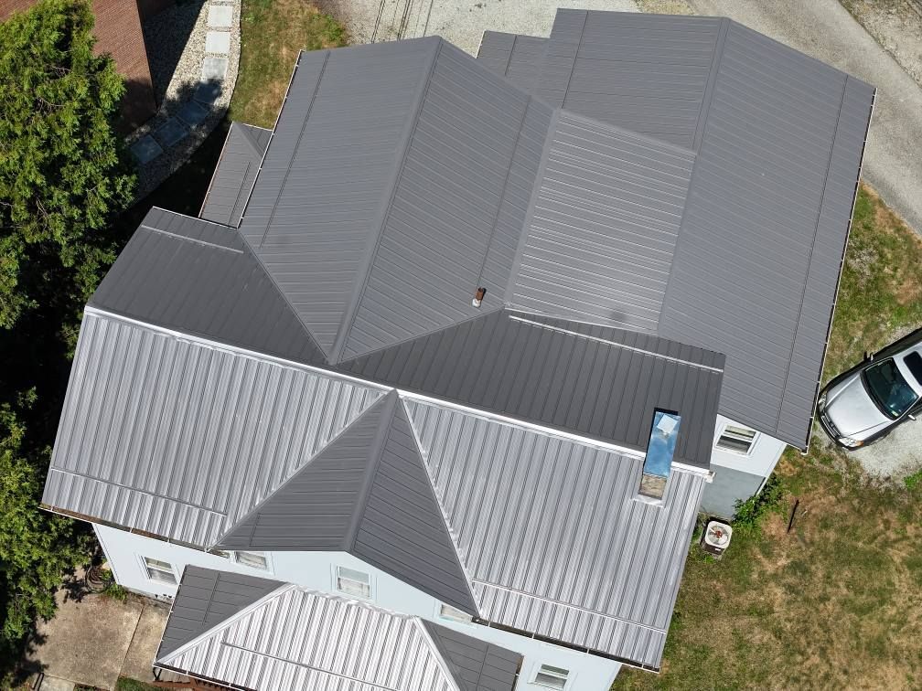 An aerial view of a house with a gray roof and a car parked in front of it.
