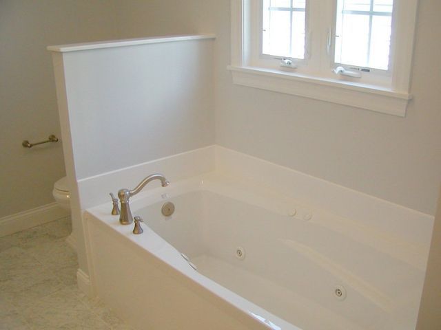 A bathtub in a bathroom next to a window