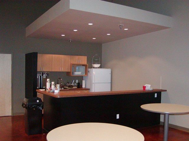 A kitchen with two tables and a refrigerator