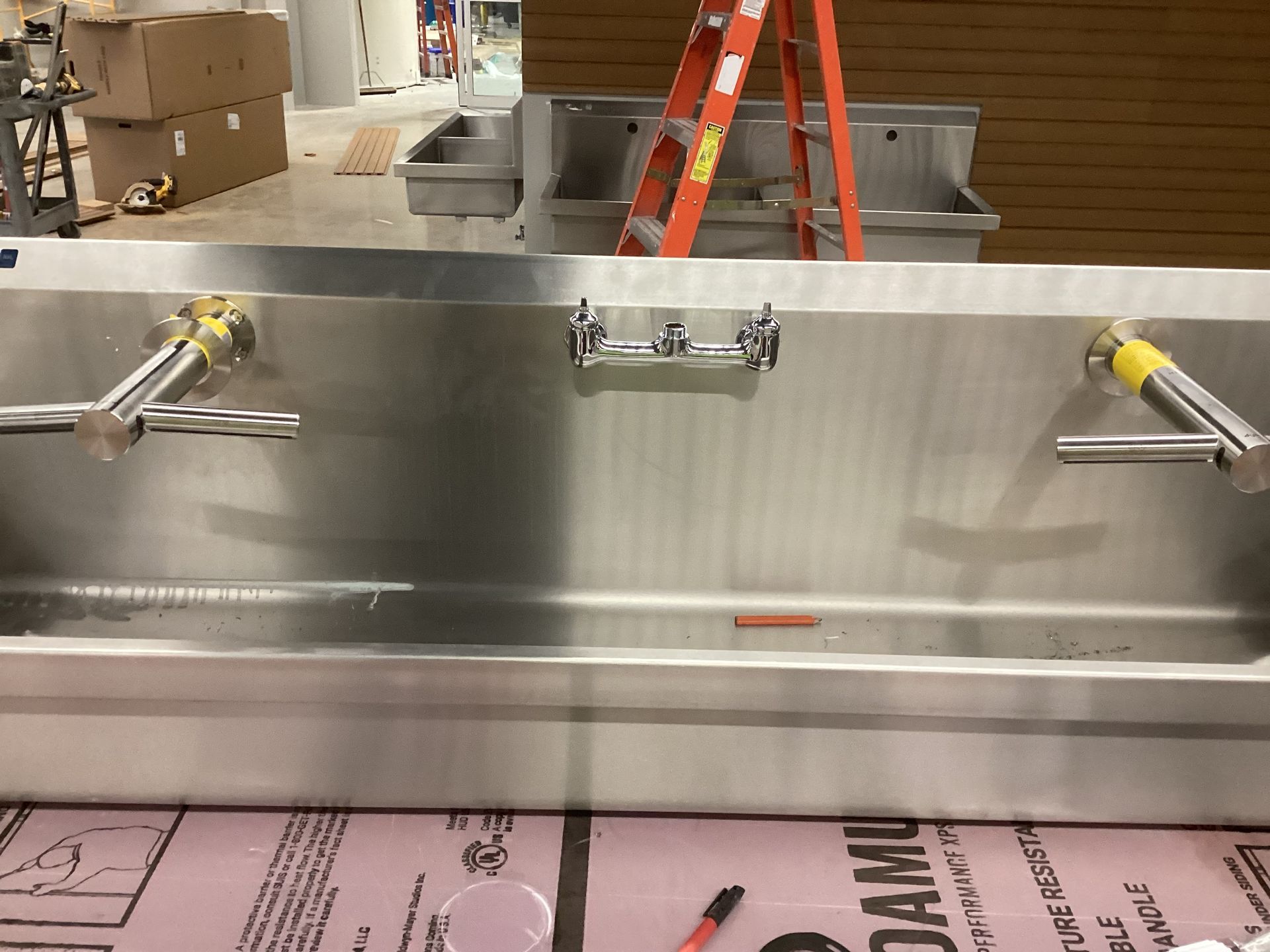 A stainless steel sink with a ladder in the background