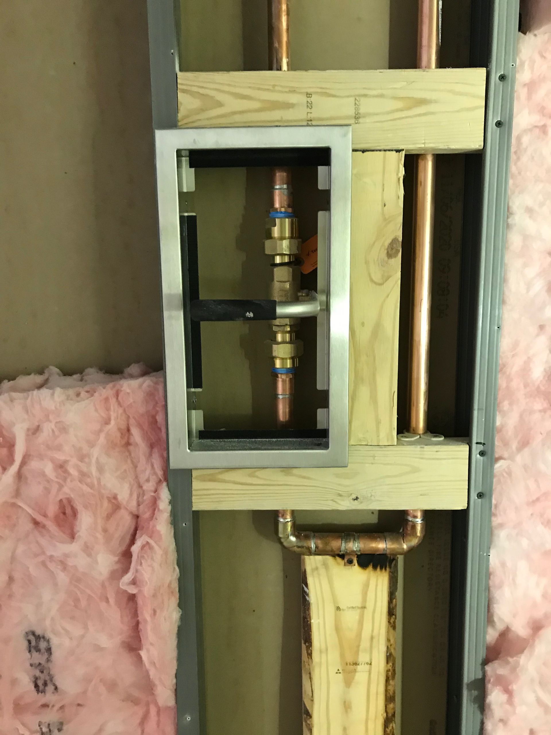 A copper pipe is being installed in a wall