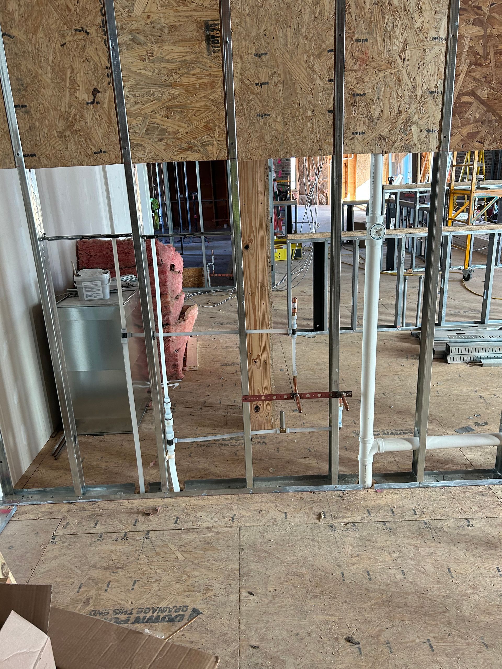 A man is standing in a room with a ladder behind a wall.