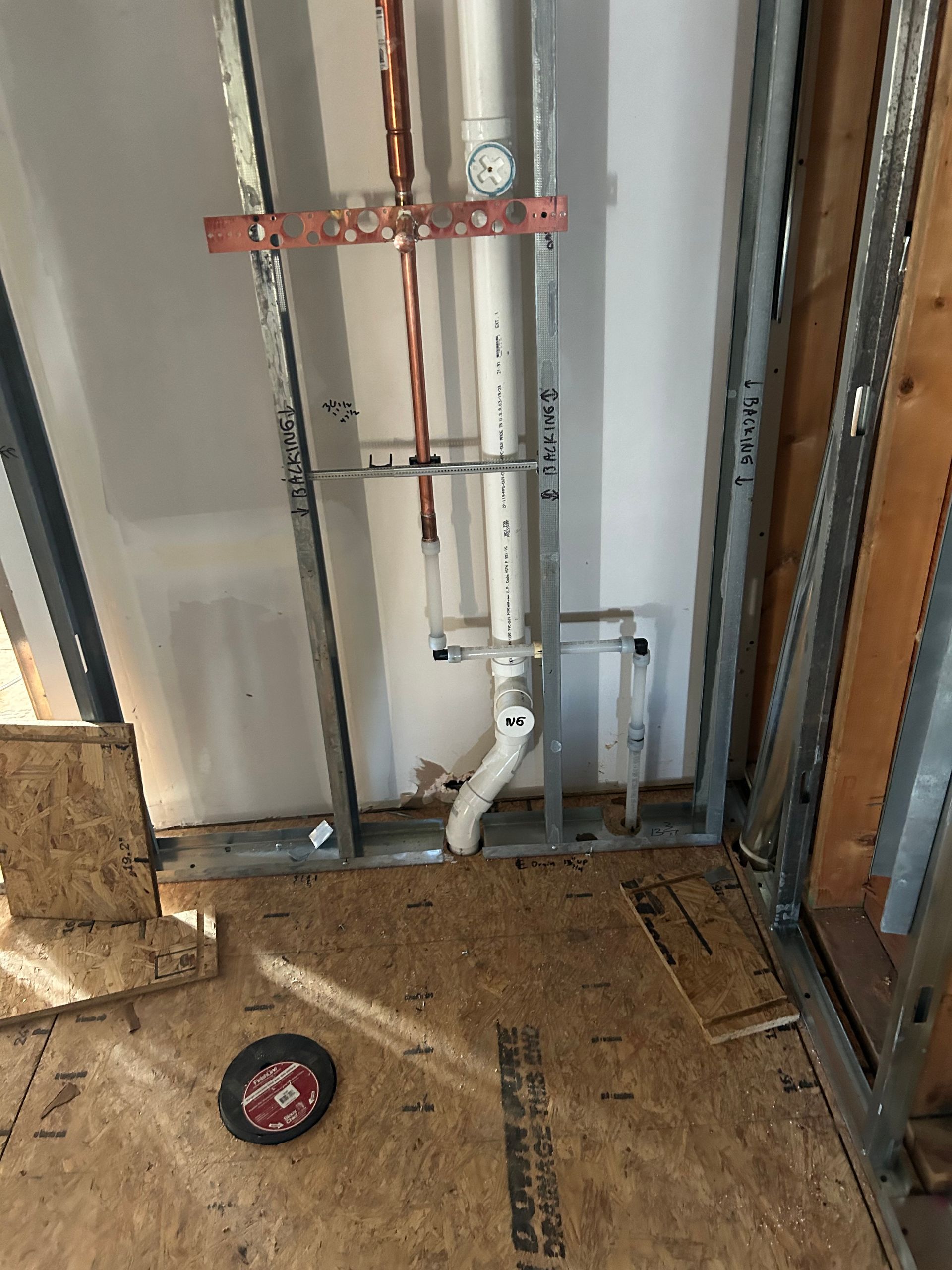 A pipe is being installed in a bathroom under construction.