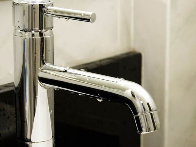 A close up of a chrome faucet in a bathroom.
