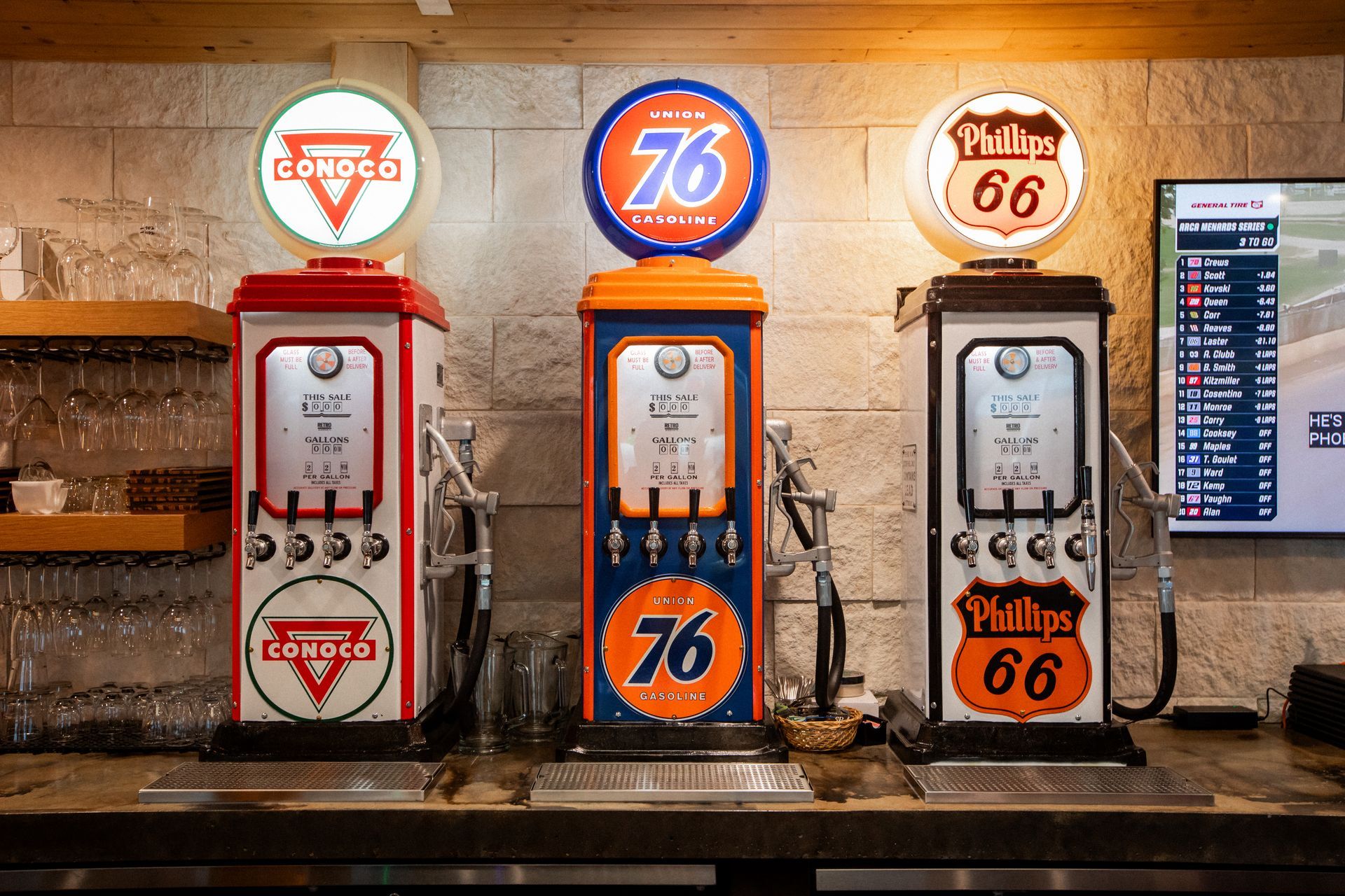 Three vintage gas pump beer taps with logos: Conoco, 76, and Phillips 66 on a bar.