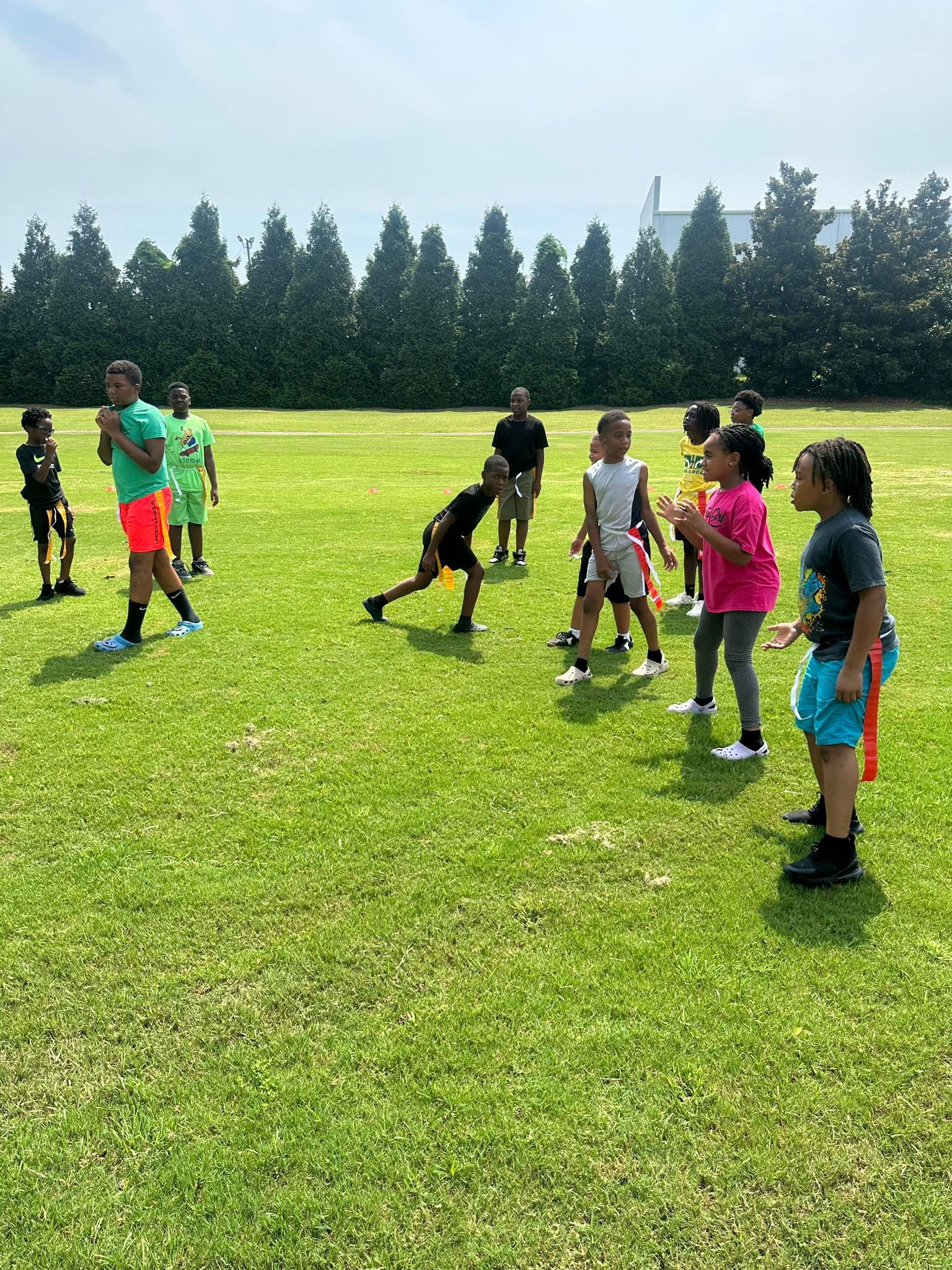 Children playing flag football on a grassy field on a sunny day.