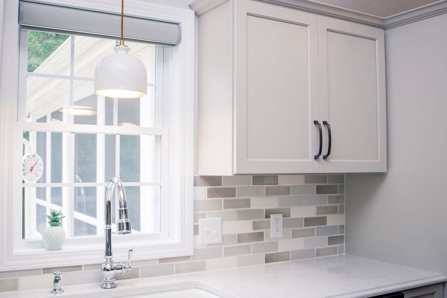 Kitchen with white cabinets, subway tile backsplash, and a sink under a window.