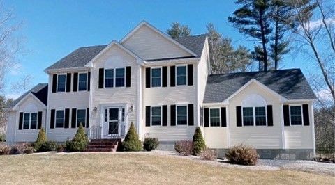 Two-story beige house with black shutters on a sunny day.