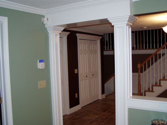 White trim frames an archway with green and brown walls, leading to a closet and staircase.