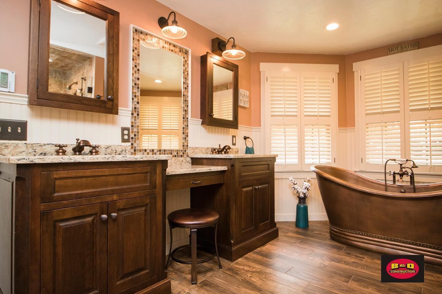 Bathroom with copper tub, wood vanities, mirrors, and shuttered windows.