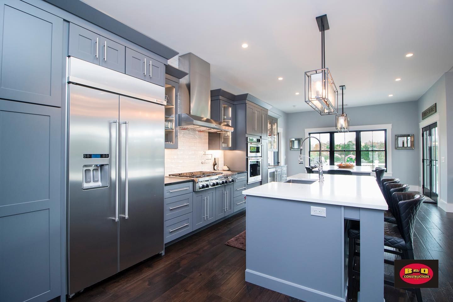 Gray kitchen with stainless steel appliances, white countertop island, dark wood floors.