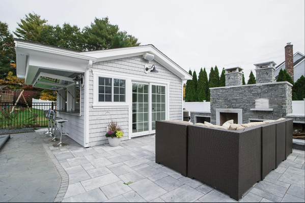 Outdoor patio with a gray cottage, bar, fireplace, and seating area.