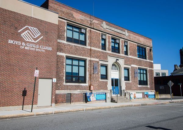 Exterior of the Boys & Girls Club of Greater Youth, brick building with blue doors and windows, sunny day.