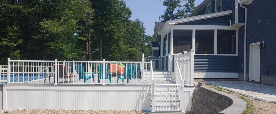 A blue house with a screened porch and pool deck with white railings.