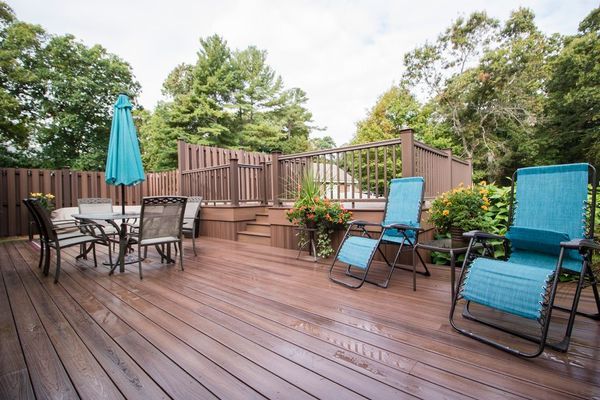 Wooden deck with outdoor furniture, umbrella, and surrounding trees.