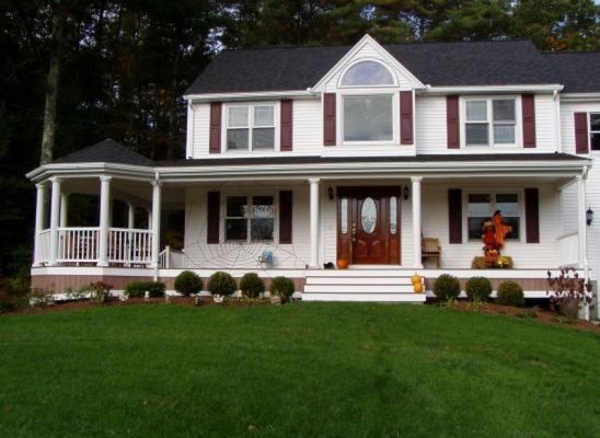 Two-story white house with maroon shutters and a porch, set on a green lawn.
