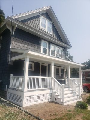 Two-story house with dark gray siding, white trim, porch, and steps.