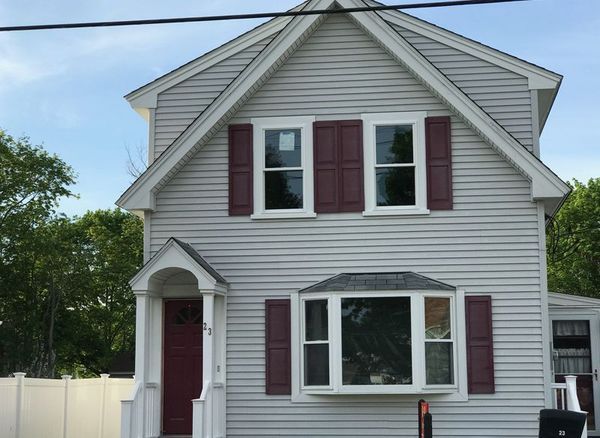 Two-story light gray house with maroon shutters and door, and a bay window.