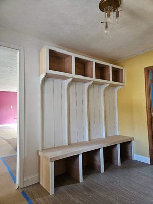 Built-in entryway bench with cubby shelves and vertical paneling, painted white with natural wood bench.