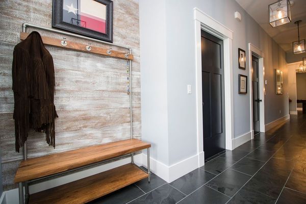 Hallway with coat rack and bench, light blue walls, dark doors, and slate floor.