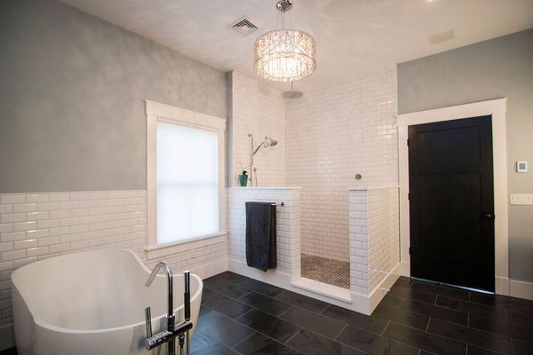 Modern bathroom with a white soaking tub, shower, and black tile floor.