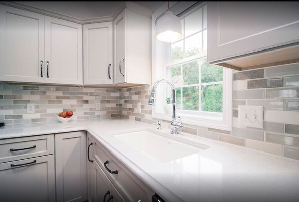 White kitchen with a sink, window, cabinets, and tile backsplash.