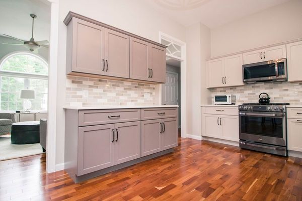 Modern kitchen with gray cabinets, stainless steel appliances, and hardwood floors.
