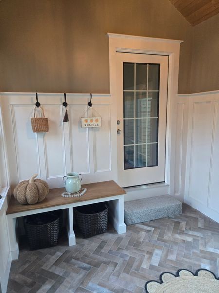 Entryway with a bench, baskets, wall hooks, and a glass door with step up.  Herringbone floors.