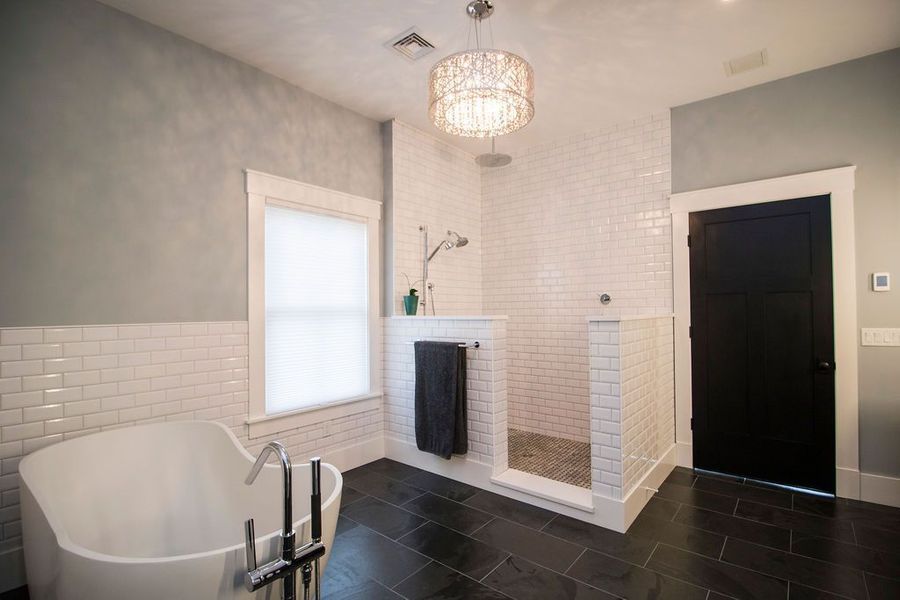 Elegant modern bathroom with a white tub, shower, and black floors.
