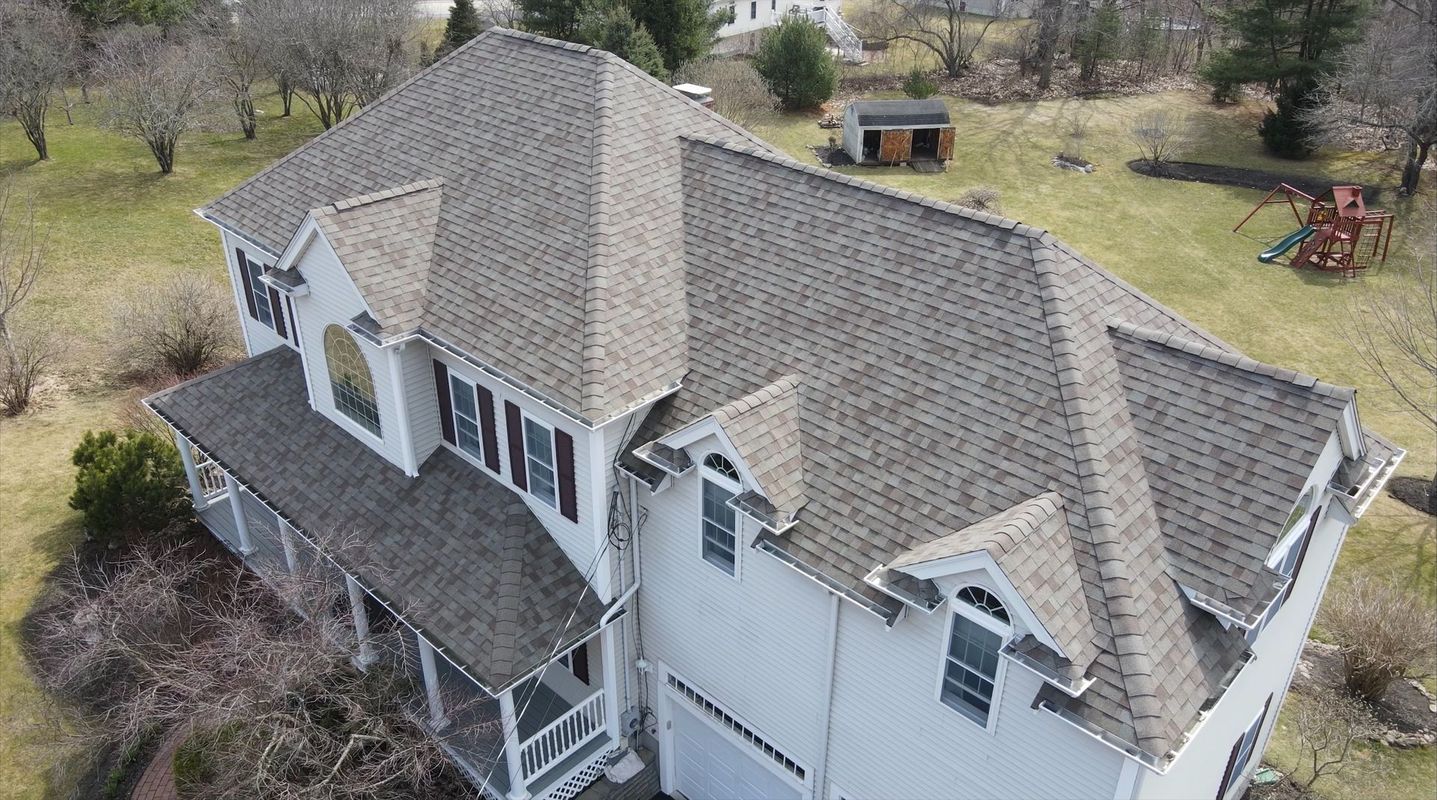 Overhead view of a two-story house with a brown roof and white siding, in a grassy yard.
