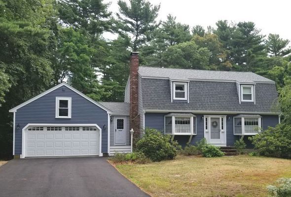 Blue house with a two-car garage and a black driveway, surrounded by green trees.