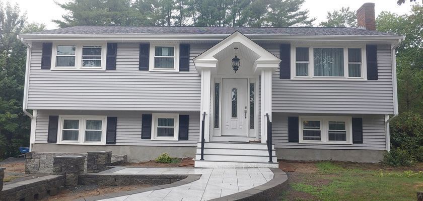 Gray suburban house with white trim, black shutters, and a brick chimney.