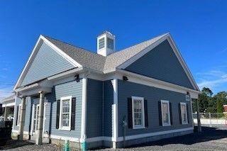 Blue building with white trim, windows, and a small cupola against a blue sky.