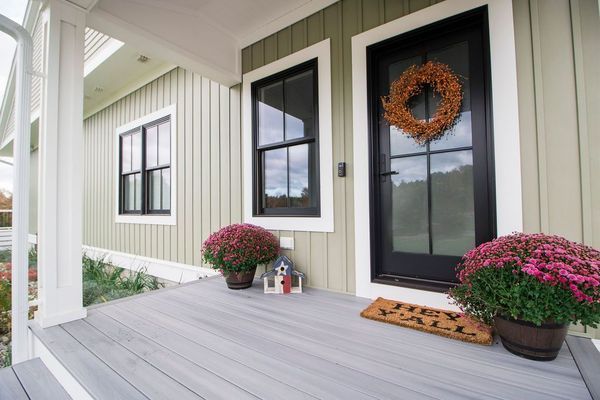 Front porch with black door, wreath, potted mums, and 