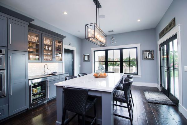 Gray kitchen with island, black accents, and large windows; view of backyard.