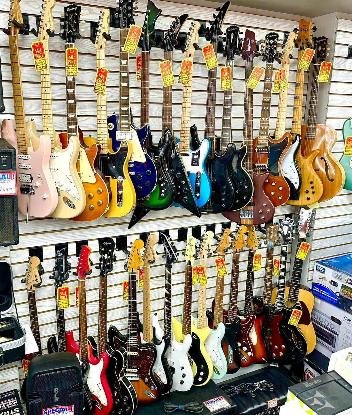 Guitars of various colors and styles displayed in a store.
