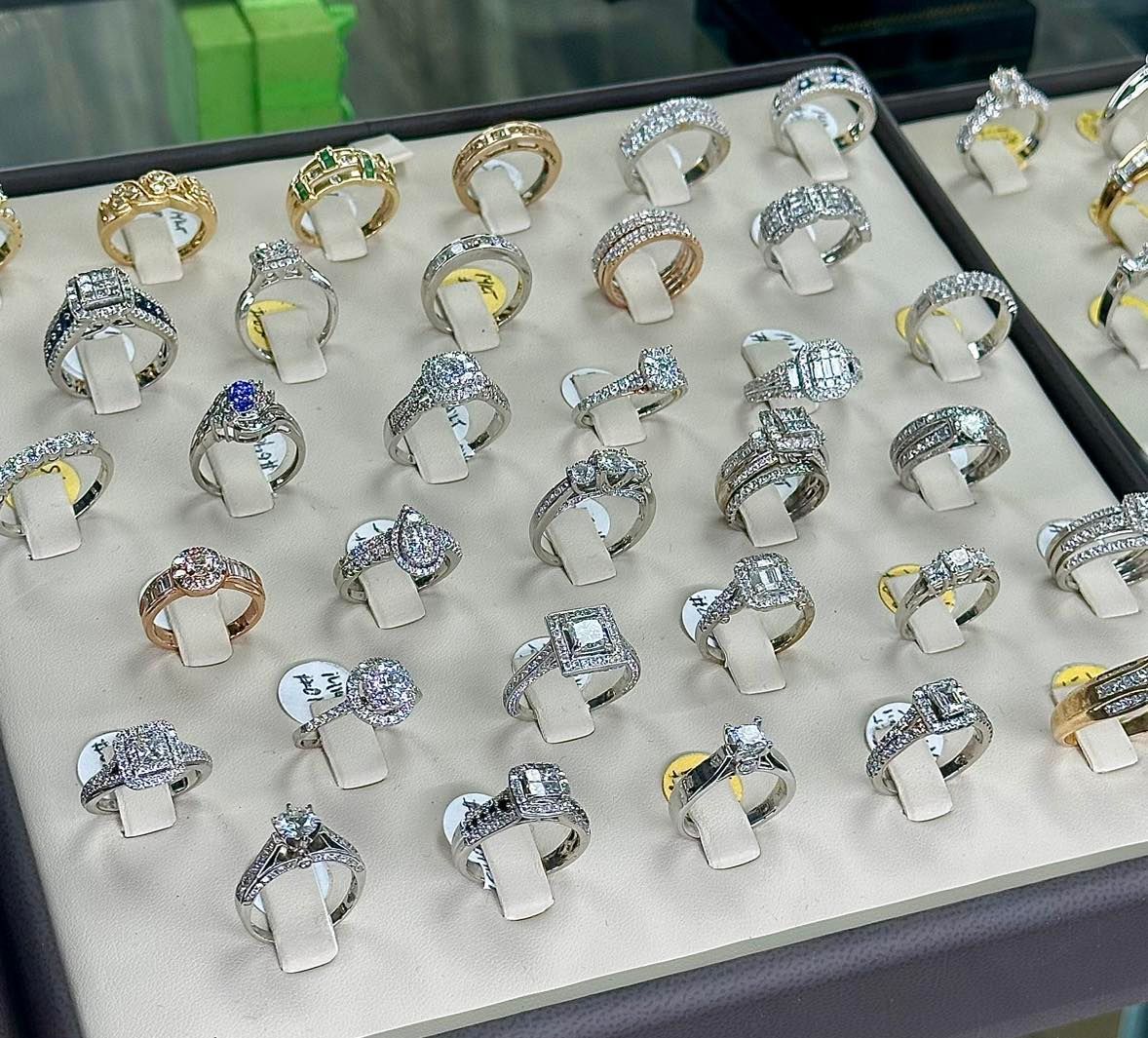 Jewelry display case with many ornate rings, most silver with clear stones, some gold.