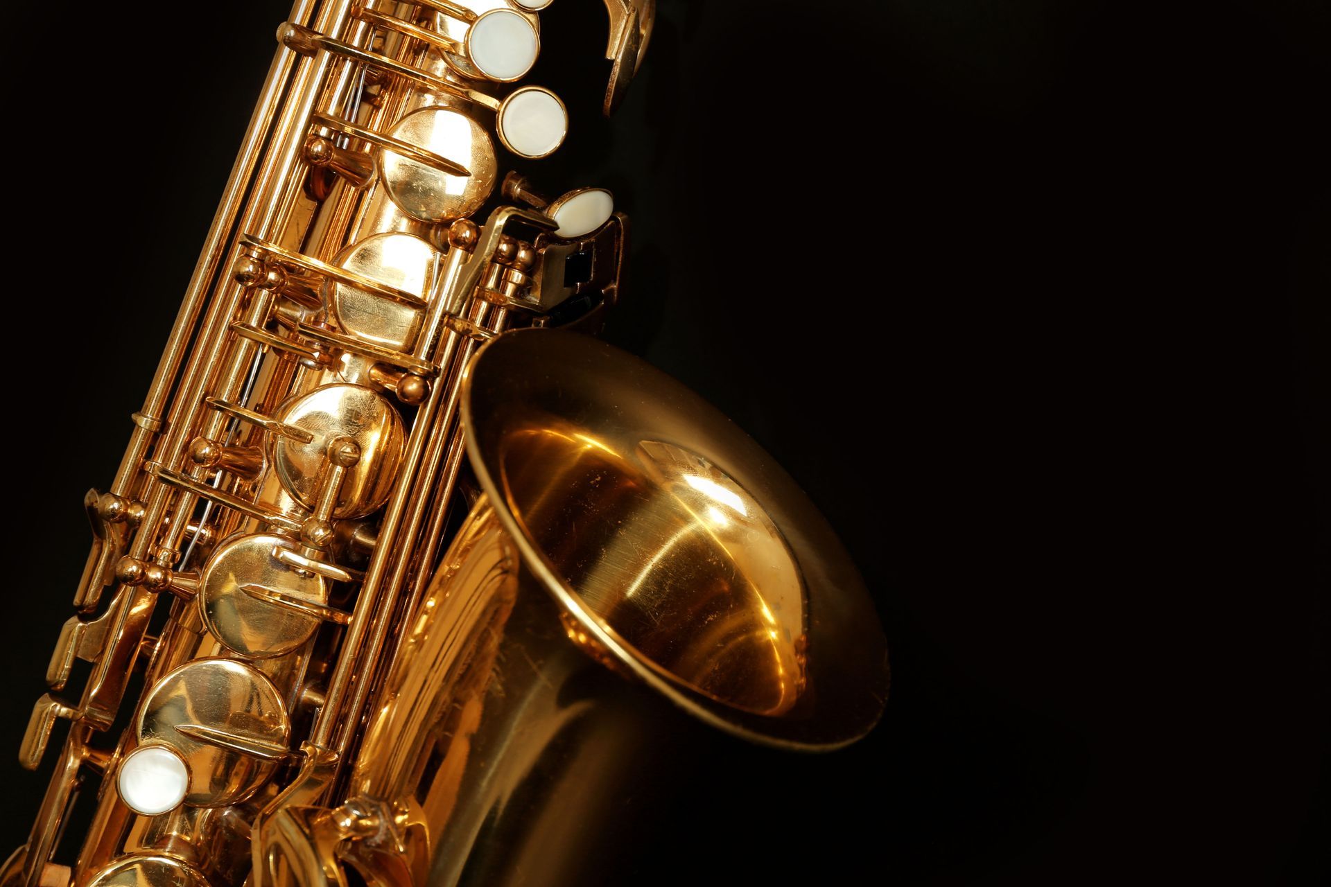 Gold saxophone against a black background.