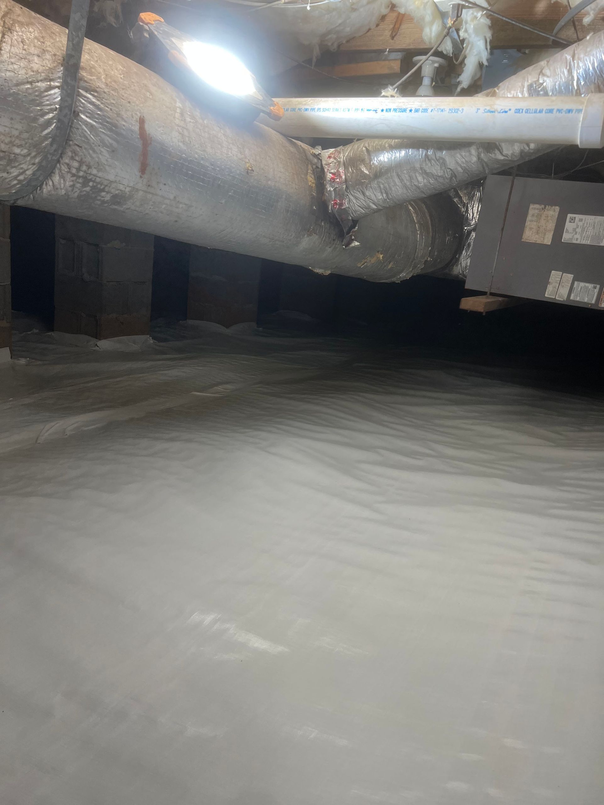 Dark crawl space; ductwork, pipes, and beams above a surface.
