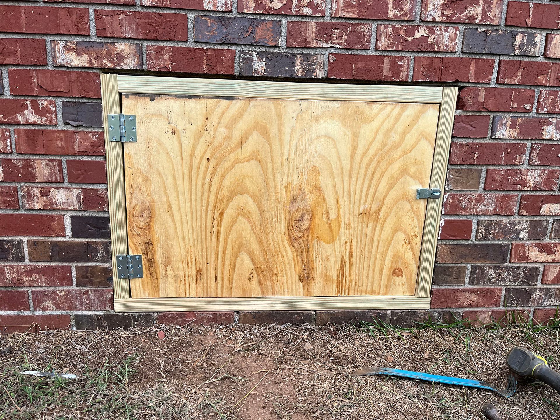 Wooden plywood door with wood trim on brick wall.
