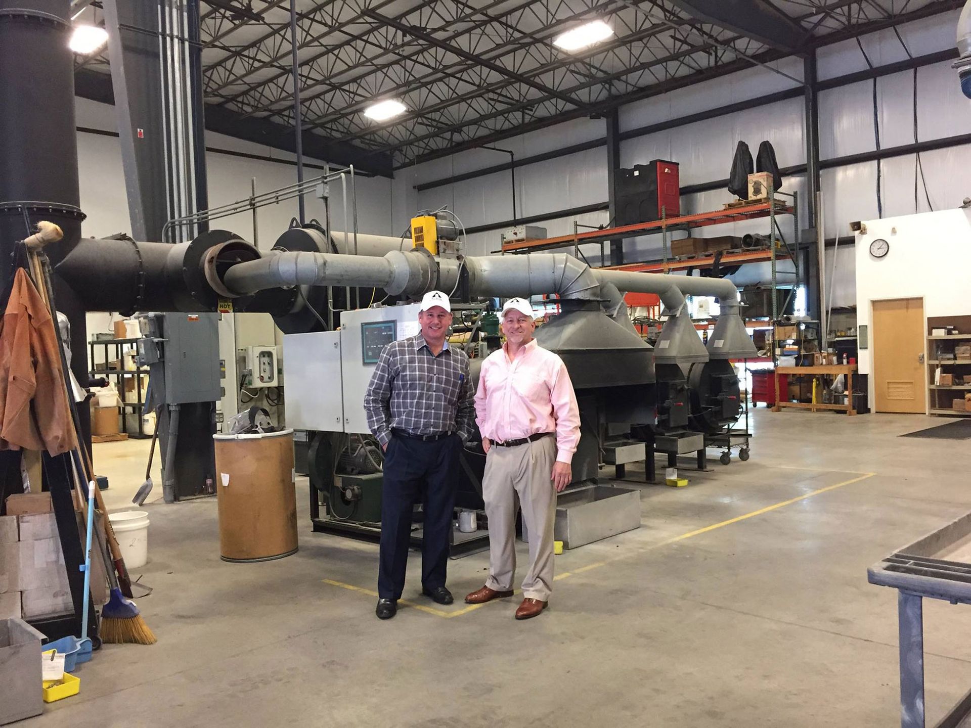 Two men are standing next to each other in a factory.