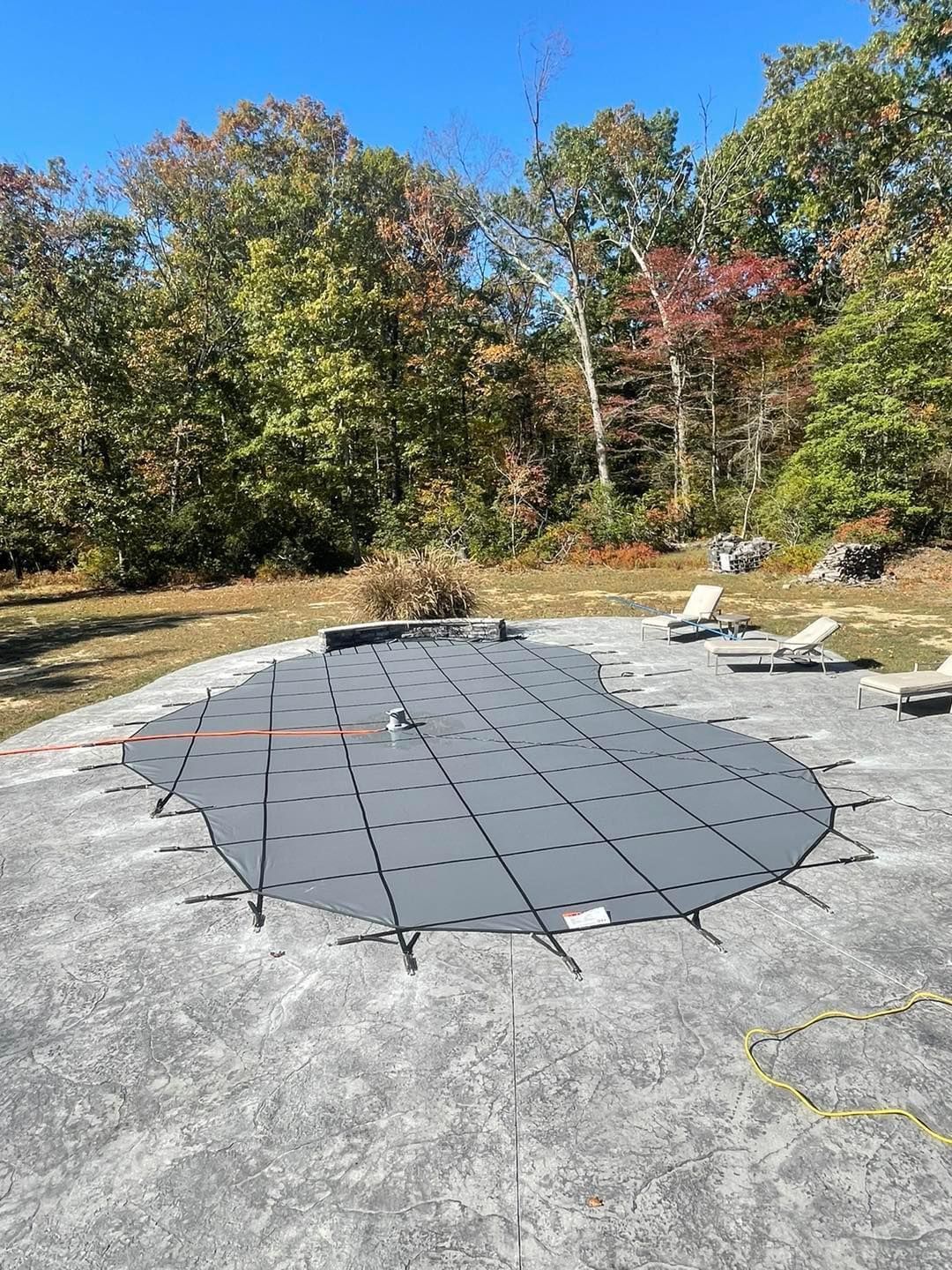 A swimming pool with a cover on it is sitting on top of a concrete patio.